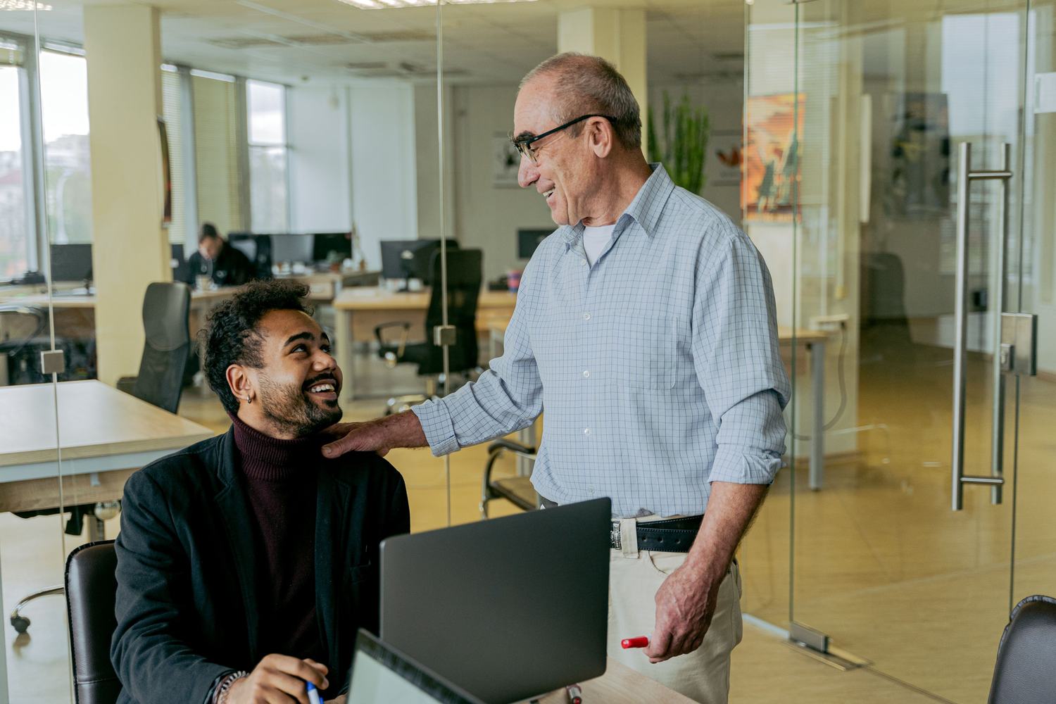 An older business owner and a younger successor talking in a workshop